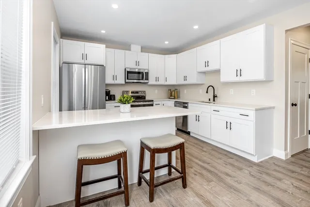 a kitchen with stainless steel appliances a sink a stove a refrigerator cabinets and a window