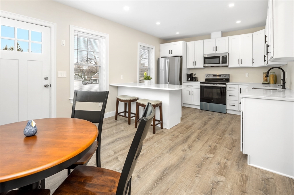 242 Atlantic Avenue, Unit 2 Hull, MA 02045 - Photo 8 of 21 a kitchen with stainless steel appliances granite countertop a stove a refrigerator a kitchen island with a dining table and chairs