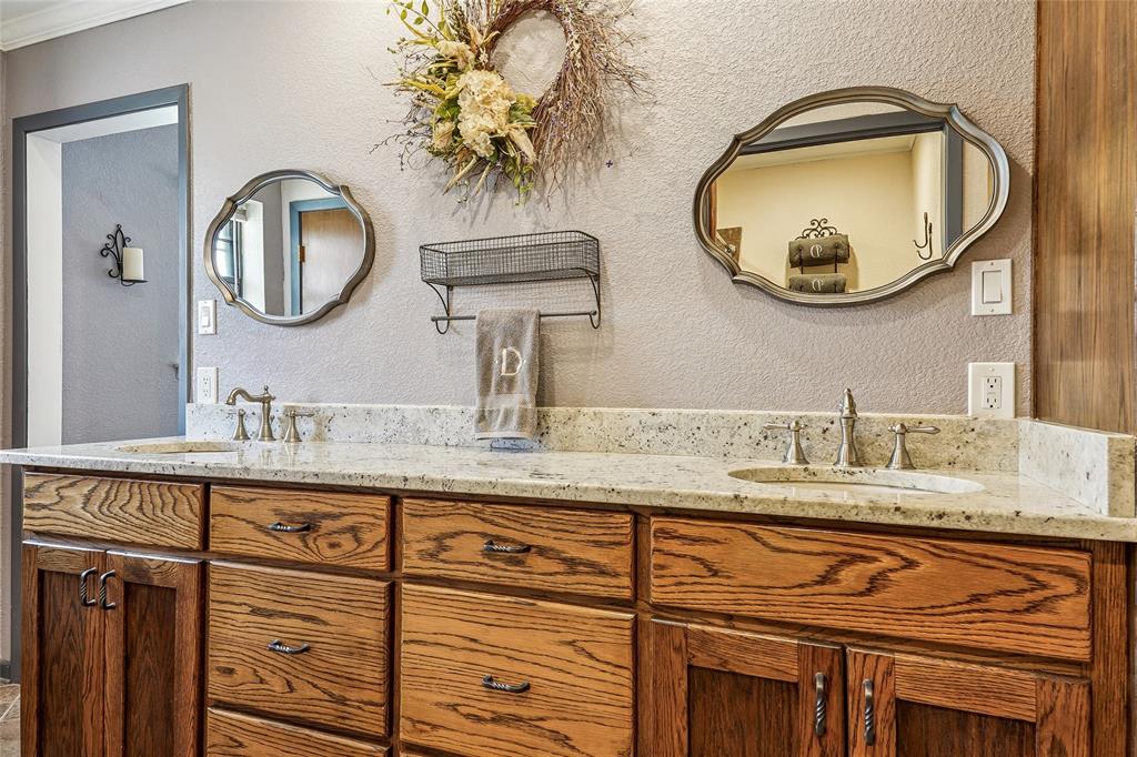 908 North Maple Street Muenster, TX 76252 - Photo 17 of 40 a bathroom with a granite countertop double vanity sinks and a mirror