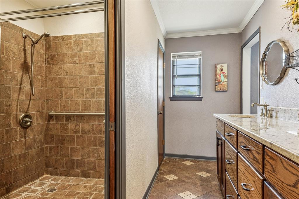 908 North Maple Street Muenster, TX 76252 - Photo 18 of 40 a bathroom with a granite countertop shower a sink and a mirror