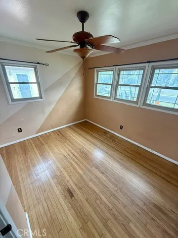 a view of an empty room with a window and wooden floor