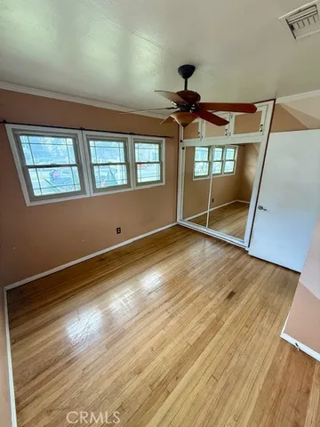 a view of an empty room with window and wooden floor