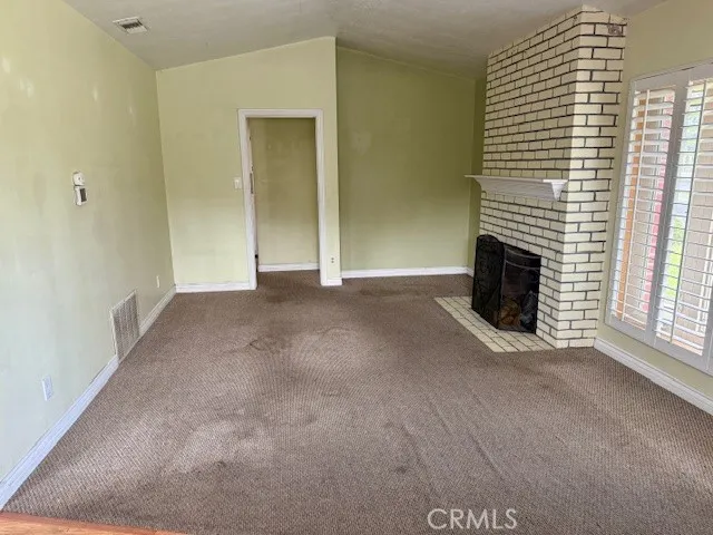 a view of an empty room with a fireplace and a window
