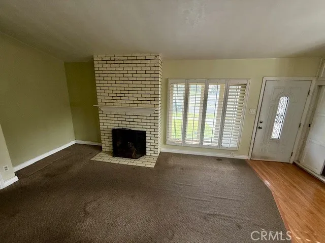 a view of an empty room with a fireplace and a window