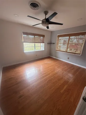 a view of an empty room with a window and wooden floor