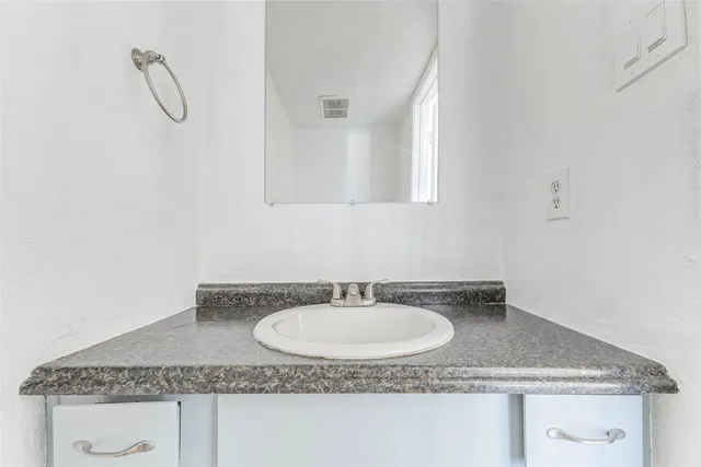 a bathroom with a granite countertop sink and a mirror