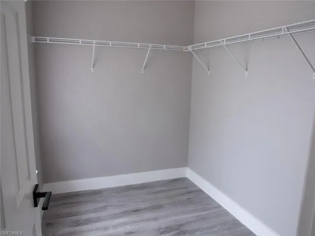 an empty room with wooden floor & closet area