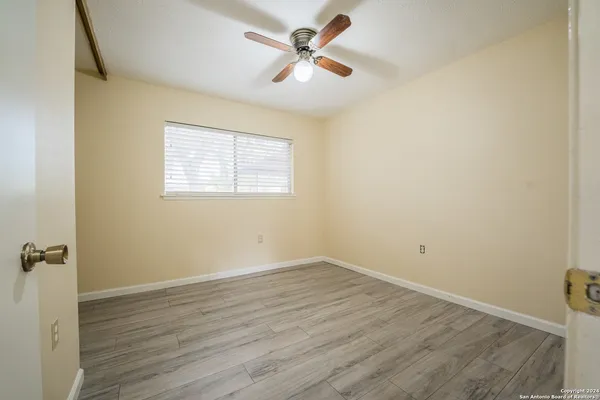 an empty room with a window and a fan