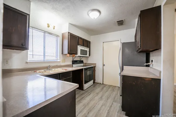 a kitchen with a sink stove top oven and refrigerator