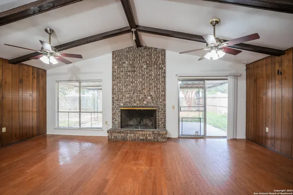 a view of an empty room with a window and wooden floor