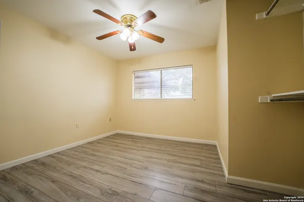 an empty room with wooden floor and a ceiling fan