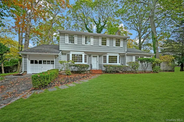 a view of a house with a big yard potted plants and large tree