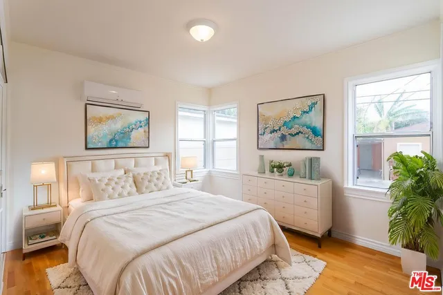 a bedroom with a bed painting on wall and a large window
