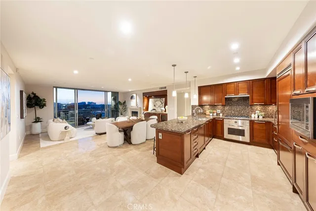 a large kitchen with kitchen island a stove a sink a dishwasher a dining table and chairs with wooden floor