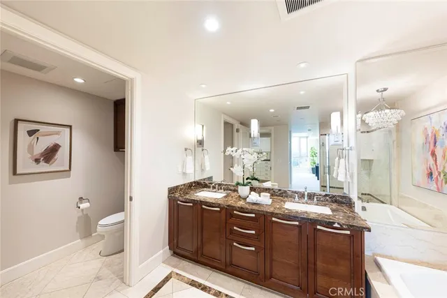 a bathroom with a granite countertop sink a toilet a mirror and a shower