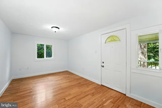 a view of empty room with window and wooden floor