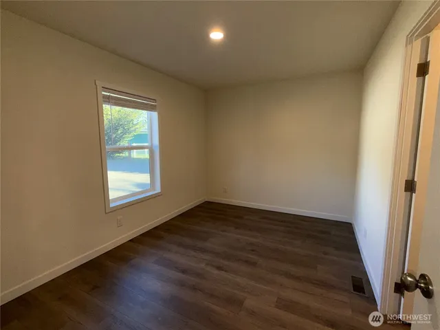 an empty room with wooden floor and a window