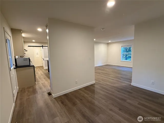 an empty room with wooden floor and a kitchen