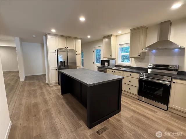 a kitchen with stainless steel appliances granite countertop a refrigerator a microwave oven a sink with island and chairs