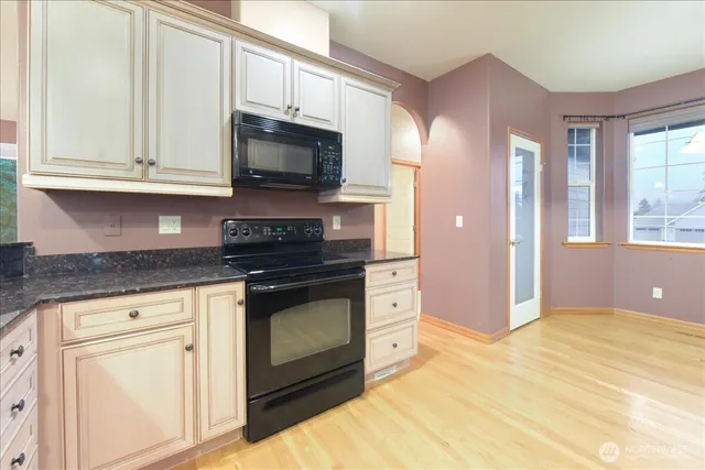 a kitchen with stainless steel appliances granite countertop a stove a sink and a microwave