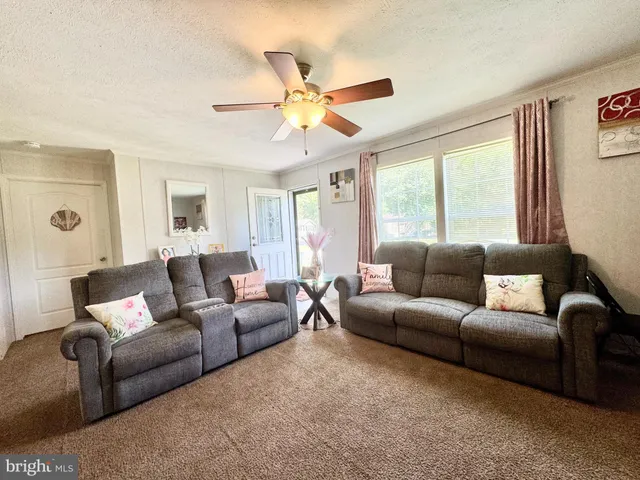 a living room with furniture a ceiling fan and a window