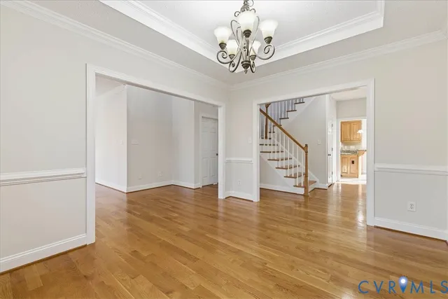 a view of an empty room with wooden floor and staircase