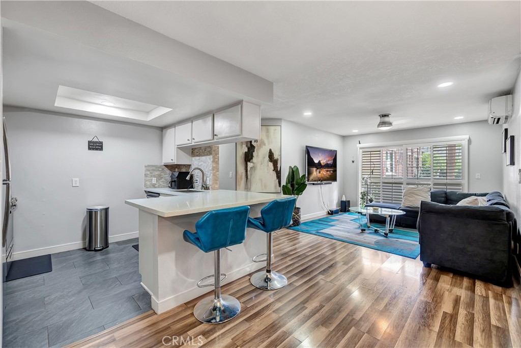 a living room with furniture a wooden floor and kitchen view