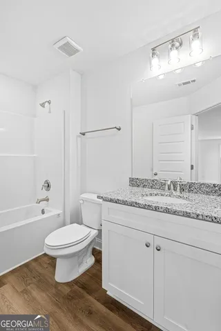 a bathroom with a granite countertop toilet a sink and a bathtub