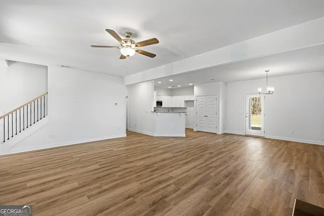a view of a livingroom with a ceiling fan wooden floor and a ceiling fan