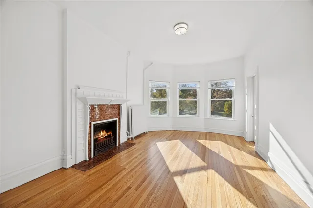 a view of empty room with wooden floor and fireplace