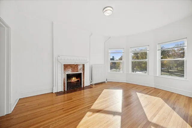a view of an empty room with window and fire place