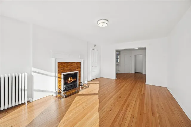 a view of empty room with wooden floor and fireplace