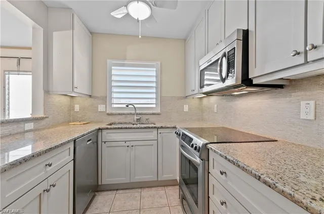 a kitchen with granite countertop cabinets stainless steel appliances a sink and a window