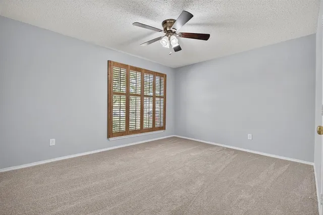 an empty room with windows and ceiling fan