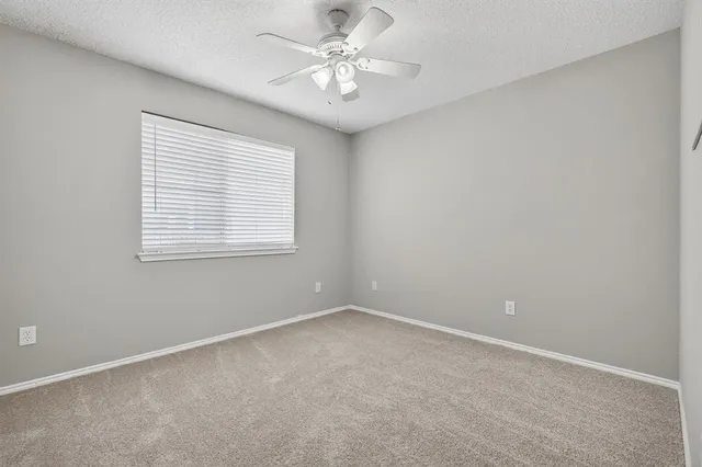 an empty room with windows and ceiling fan