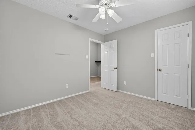 a view of an empty room with a chandelier fan