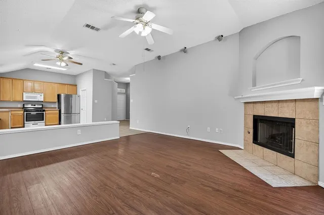a view of an empty room with a fireplace and wooden floor