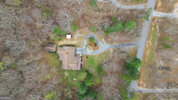 a view of a white house with a large tree and wooden fence