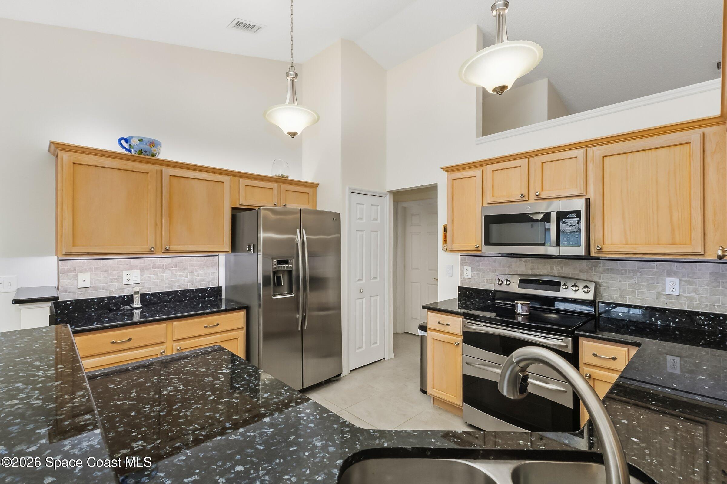 263 Mcclain Drive Melbourne, FL 32904 - Photo 14 of 56 a kitchen with stainless steel appliances granite countertop a sink a stove and a refrigerator