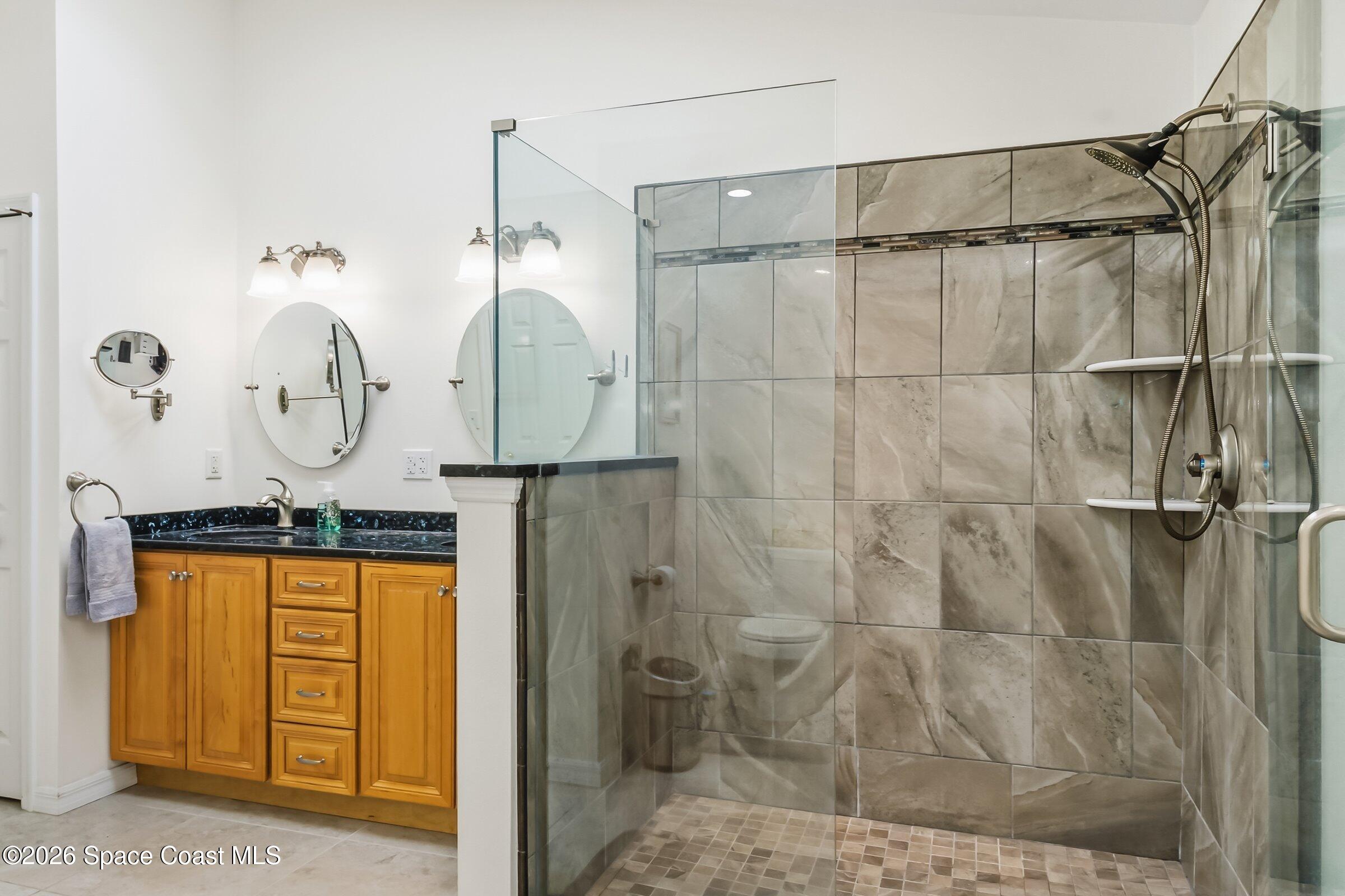 263 Mcclain Drive Melbourne, FL 32904 - Photo 25 of 56 a picture of a bathroom with a shower a mirror and a sink
