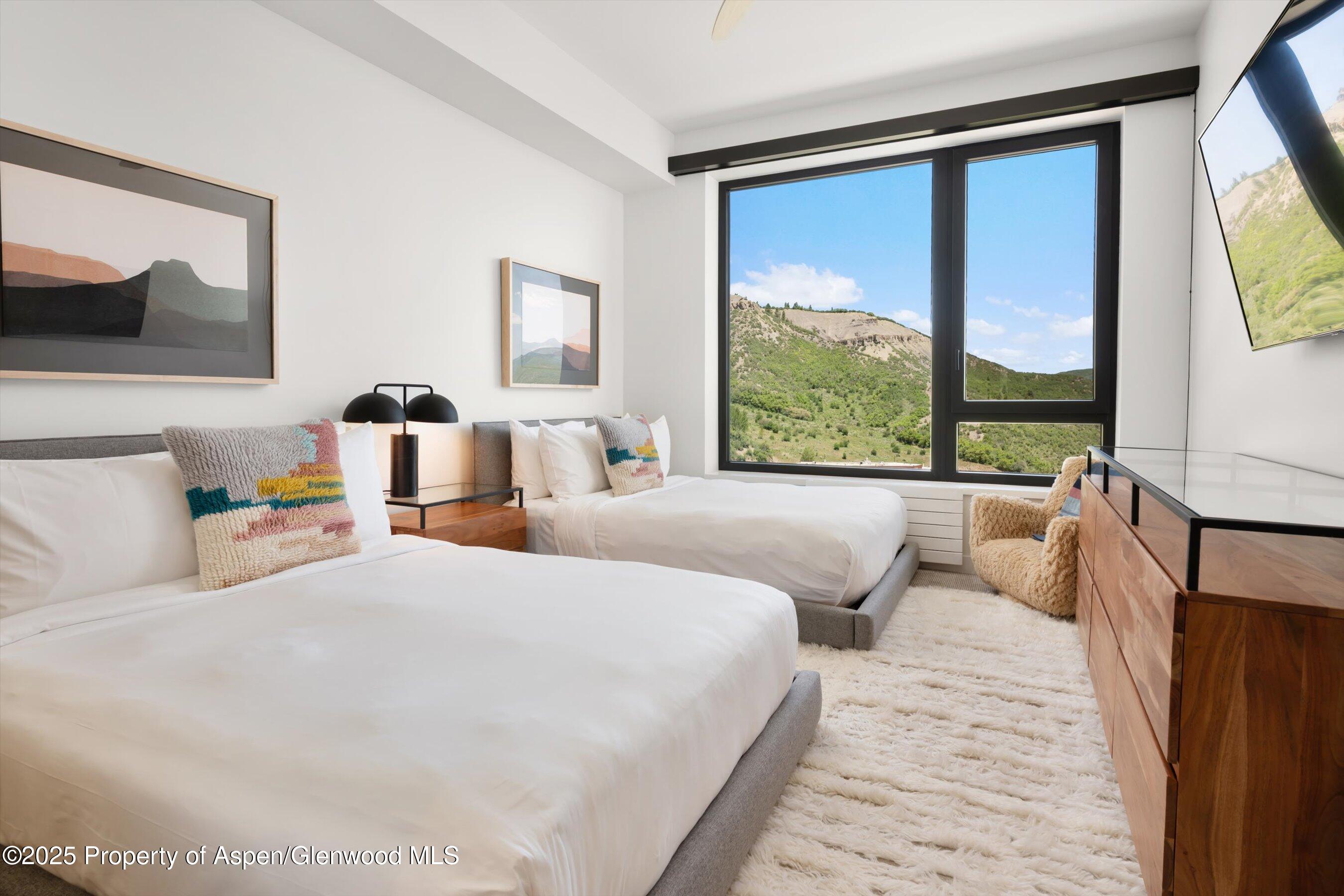 119 Wood Road, Unit 604 Snowmass Village, CO 81615 - Photo 19 of 48 a bedroom with a large bed and a large window with outer view