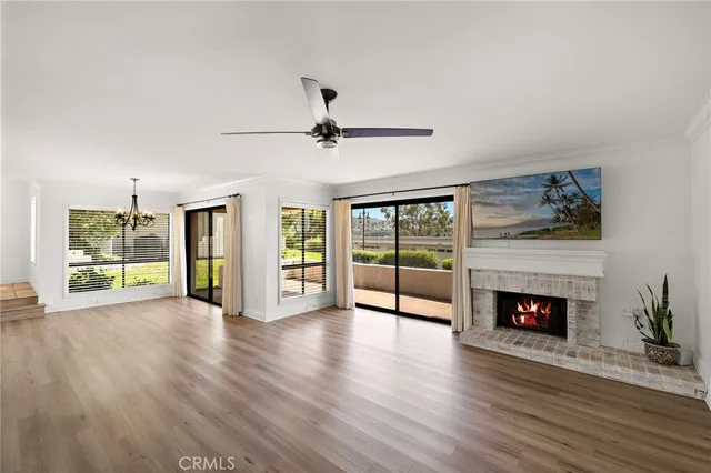 a view of an empty room with wooden floor fireplace and a window