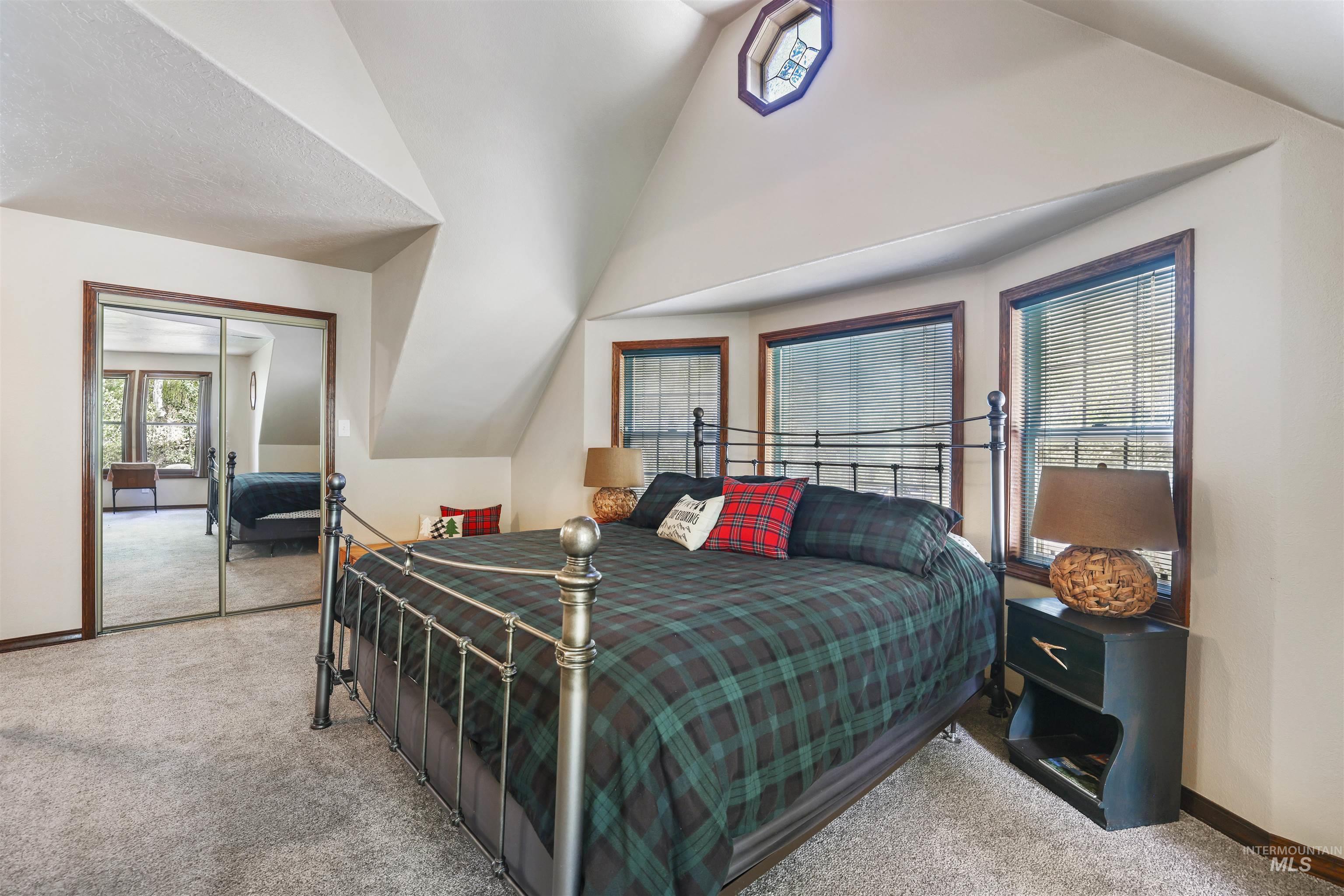 224 Dakota Road Mountain Home, ID 83647 - Photo 27 of 50 Vaulted ceiling bedroom featuring ample natural light, a decorative stained-glass window, and mirrored sliding closet doors