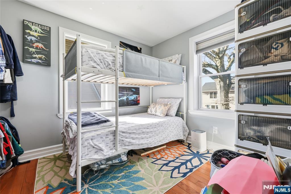 42 South Demarest Avenue Bergenfield, NJ 07621 - Photo 19 of 39 a bedroom with a bed a standing fan and a bookshelf with wooden floor
