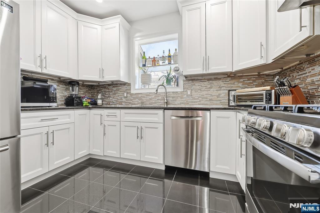 42 South Demarest Avenue Bergenfield, NJ 07621 - Photo 10 of 39 a kitchen with white cabinets stainless steel appliances and sink