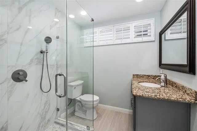 a bathroom with a granite countertop sink a toilet and a mirror