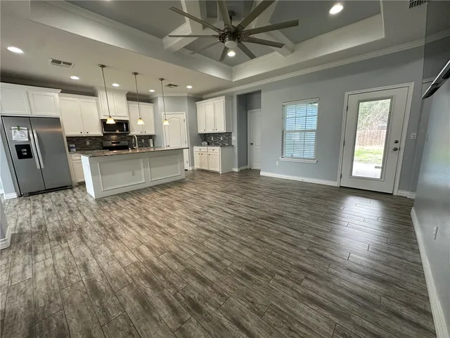 a large kitchen with stainless steel appliances kitchen island a large counter top a sink and a refrigerator