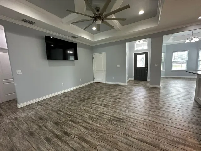 a view of an empty room with wooden floor and a ceiling fan