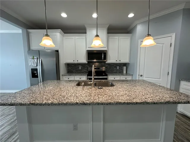 a kitchen with a sink granite counter top a stove and refrigerator