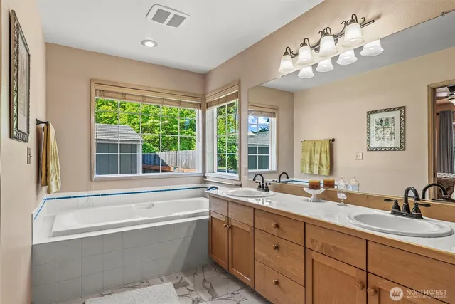 a bathroom with a tub sink double vanity and window